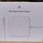 This image depicts the 85W MagSafe power adapter, which is compatible with certain MacBook models. The adapter features a magnetic DC connector that safely disconnects from the computer if someone accidentally trips over the cable. This helps prevent the computer from falling off a desk or table and potentially causing damage to both the computer and the cable. The adapter also includes an LED indicator that changes color to let you know when your laptop is charging, fully charged, or in standby mode. With its compact and portable design, this adapter is perfect for use at home, in the office, or on the go. It provides reliable power to keep your MacBook charged and ready to use whenever you need it.