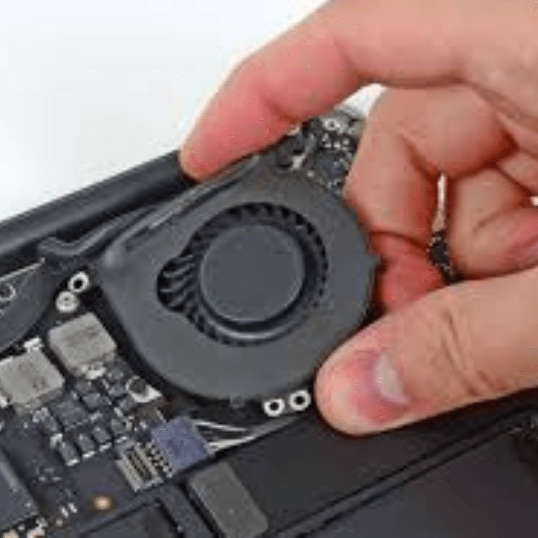 Technician unscrewing the back panel of a MacBook for fan replacement, with a new fan and tools laid out next to the laptop.